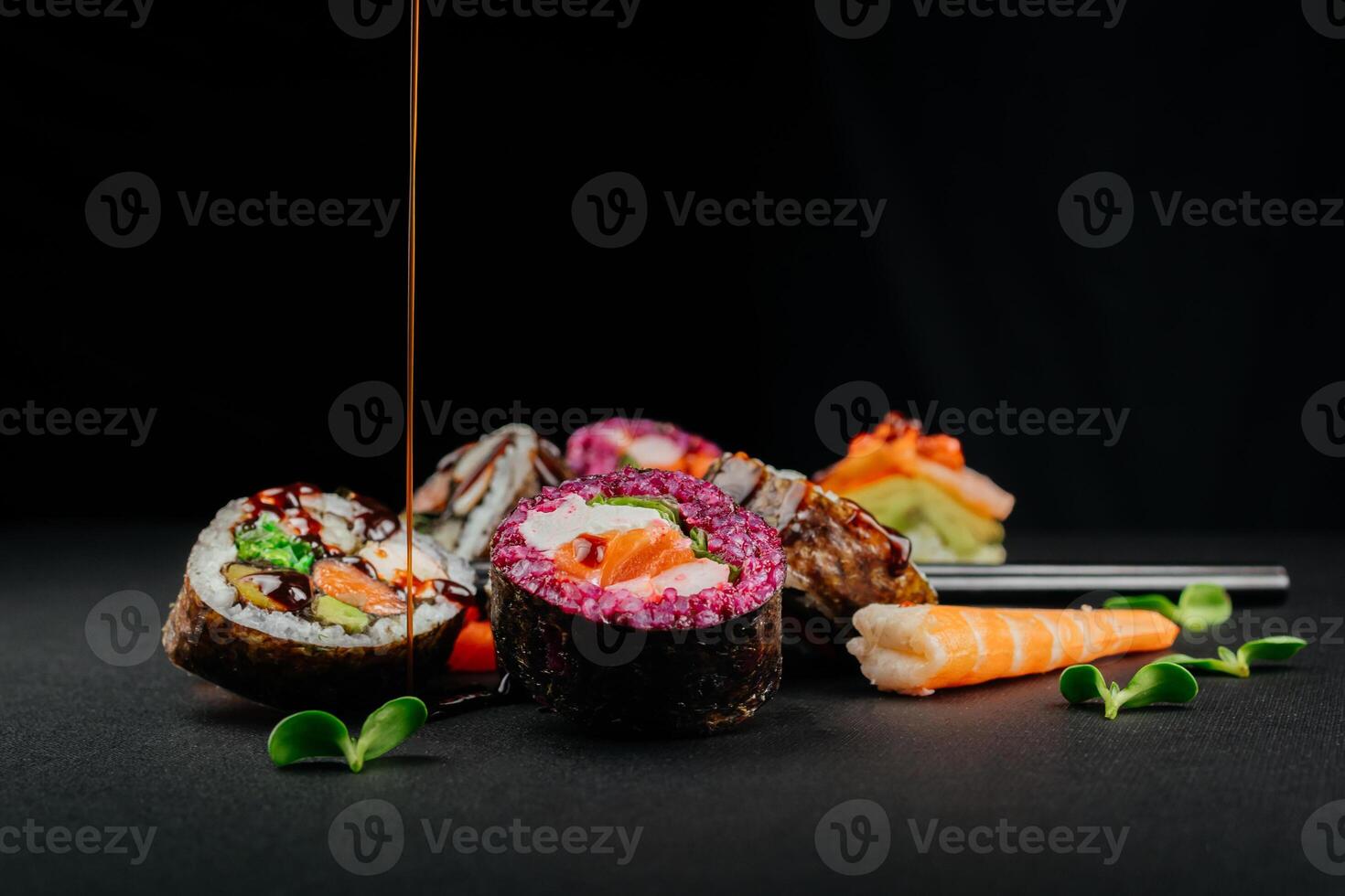 Various sushi, Japanese  lunch and side dishes and dipping teriyaki sauce on dark background. Side view of portion of Japanese sushi rolls set. Asian cuisine. Free space for your text photo