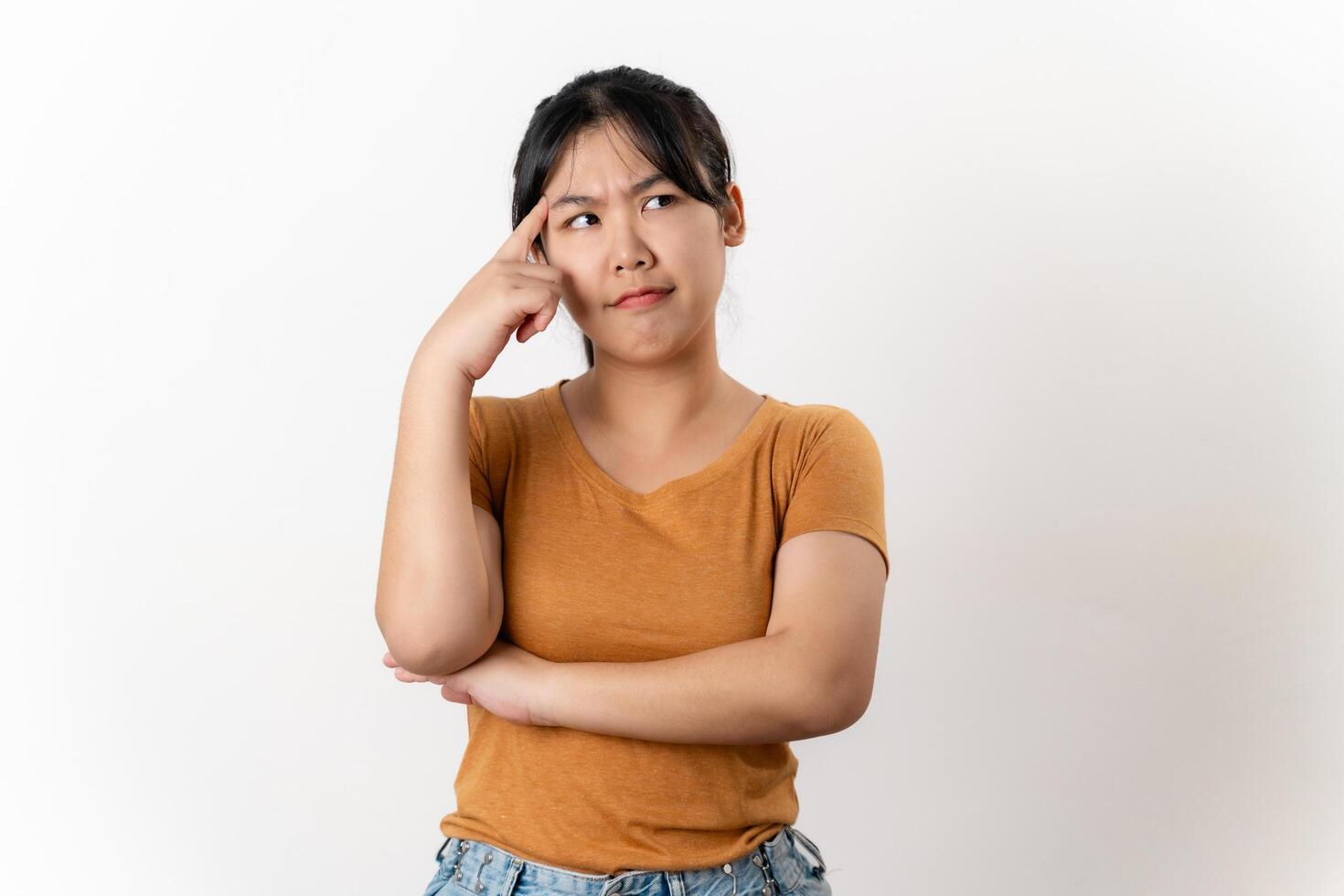 The curious thoughtful young Asian woman looks pensively standing on white background. photo