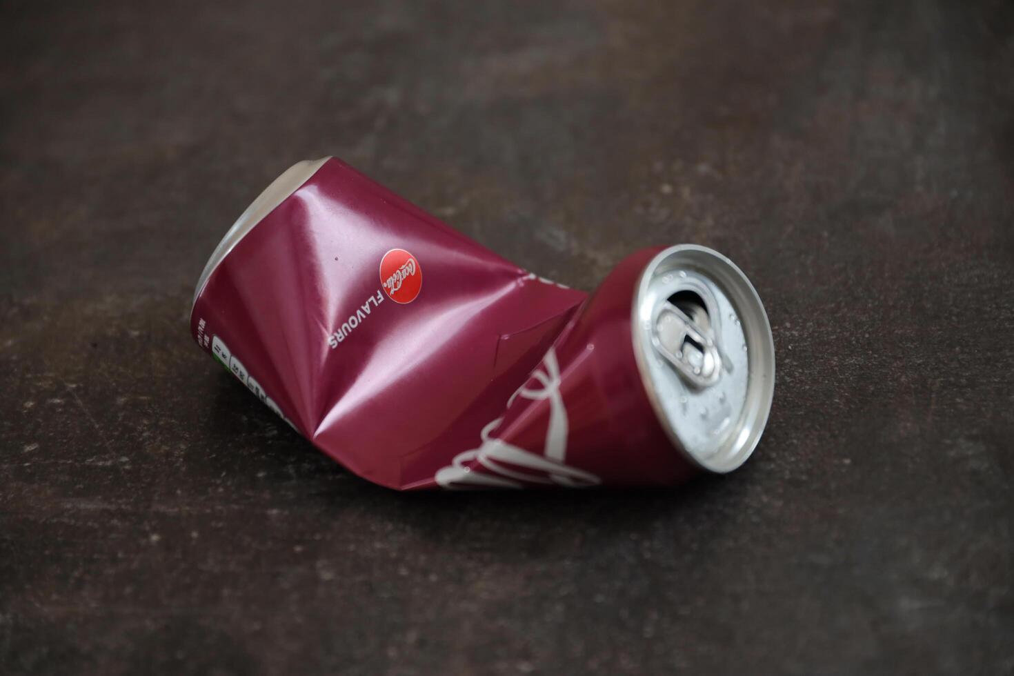 KYIV, UKRAINE - 4 MAY, 2023 Coca cola soft drink crumpled tin can with cherry flavour photo