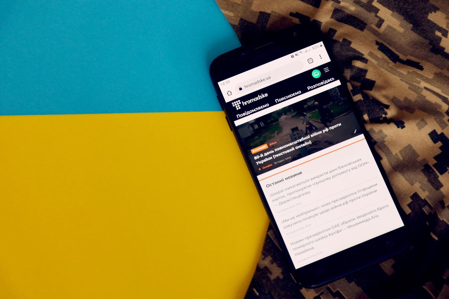 KYIV, UKRAINE - 4 MAY, 2023 Hromadske ukrainian news portal on smartphone screen with ukrainian flag and camouflage fabric photo