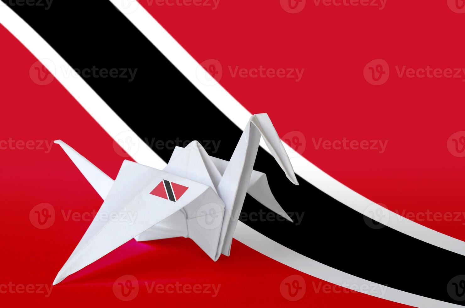 Trinidad and Tobago flag depicted on paper origami crane wing. Handmade arts concept photo