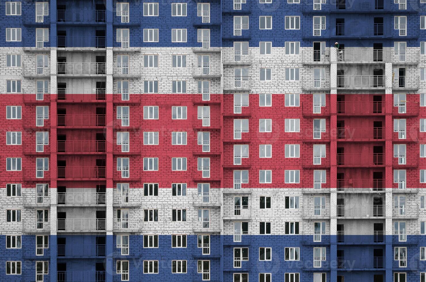 Costa Rica flag depicted in paint colors on multi-storey residental building under construction. Textured banner on brick wall background photo