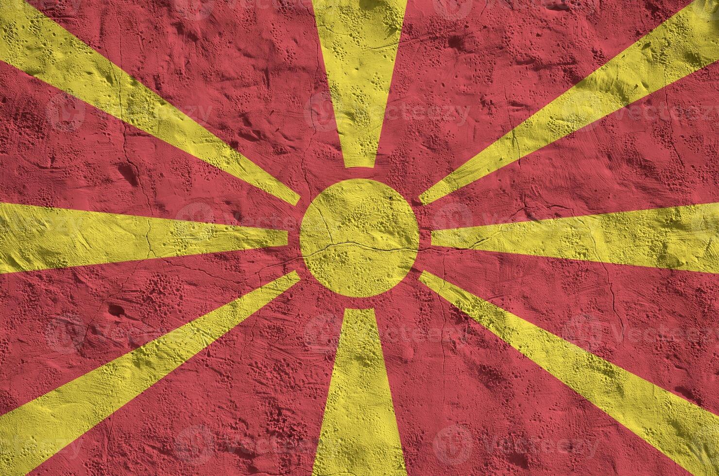 Macedonia flag depicted in bright paint colors on old relief plastering wall. Textured banner on rough background photo