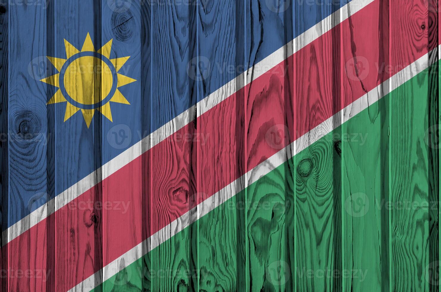 Namibia flag depicted in bright paint colors on old wooden wall. Textured banner on rough background photo