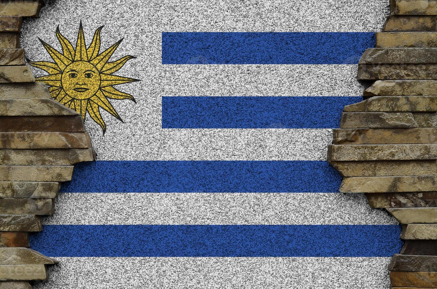 Uruguay flag depicted in paint colors on old stone wall closeup. Textured banner on rock wall background photo