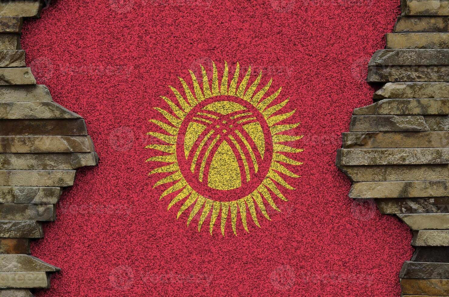 Kyrgyzstan flag depicted in paint colors on old stone wall closeup. Textured banner on rock wall background photo