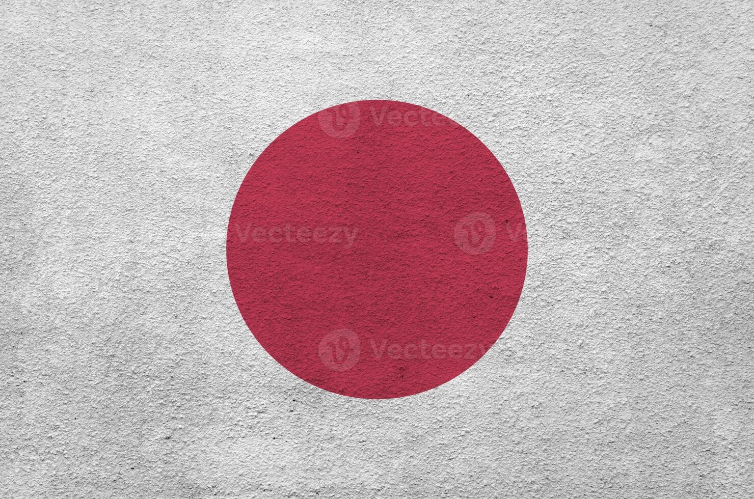 Japan flag depicted in bright paint colors on old relief plastering wall. Textured banner on rough background photo