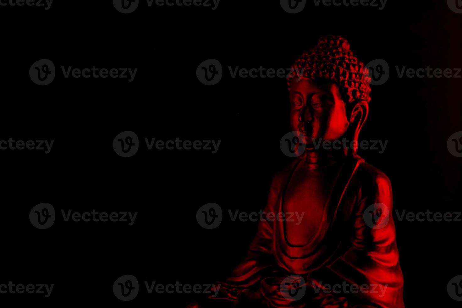 Buddha Purnima and Vesak day concept, Red Buddha statue with low key light against deep black background photo