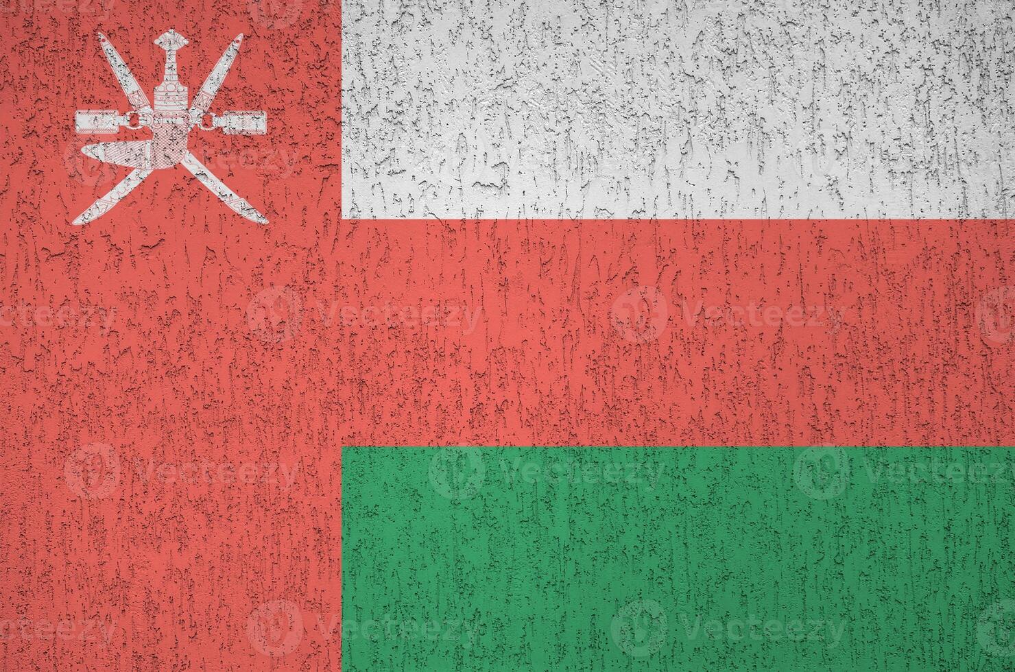 Oman flag depicted in bright paint colors on old relief plastering wall. Textured banner on rough background photo