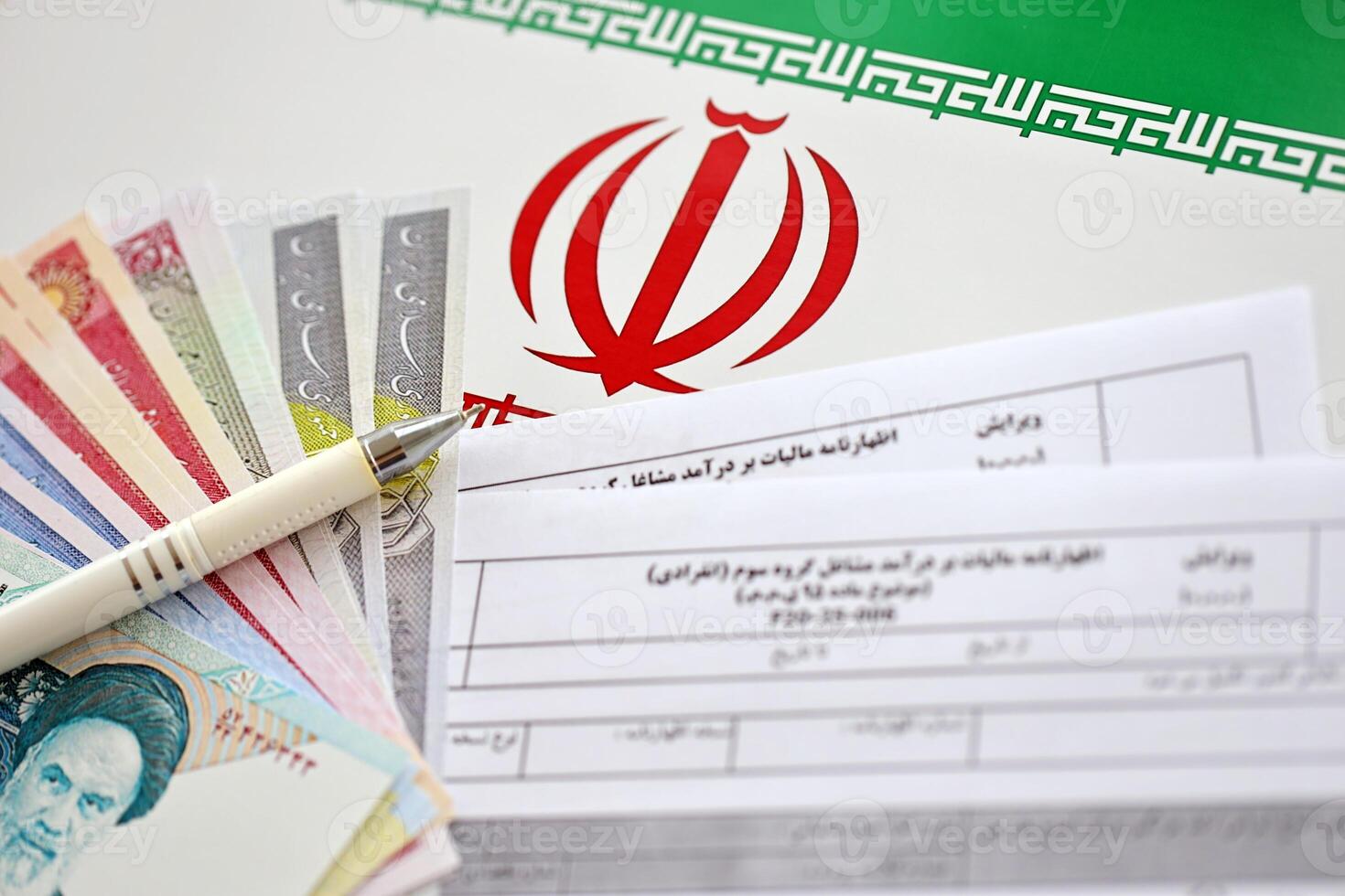 Iranian annual income tax return form F20-25-006 ready to fill on table with pen and iranian money on flag photo