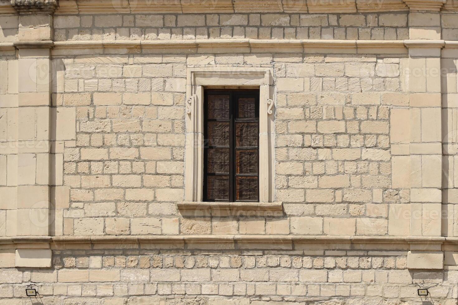 Very old window in brick stone wall of castle or fortress of 18th century. Full frame wall with window photo