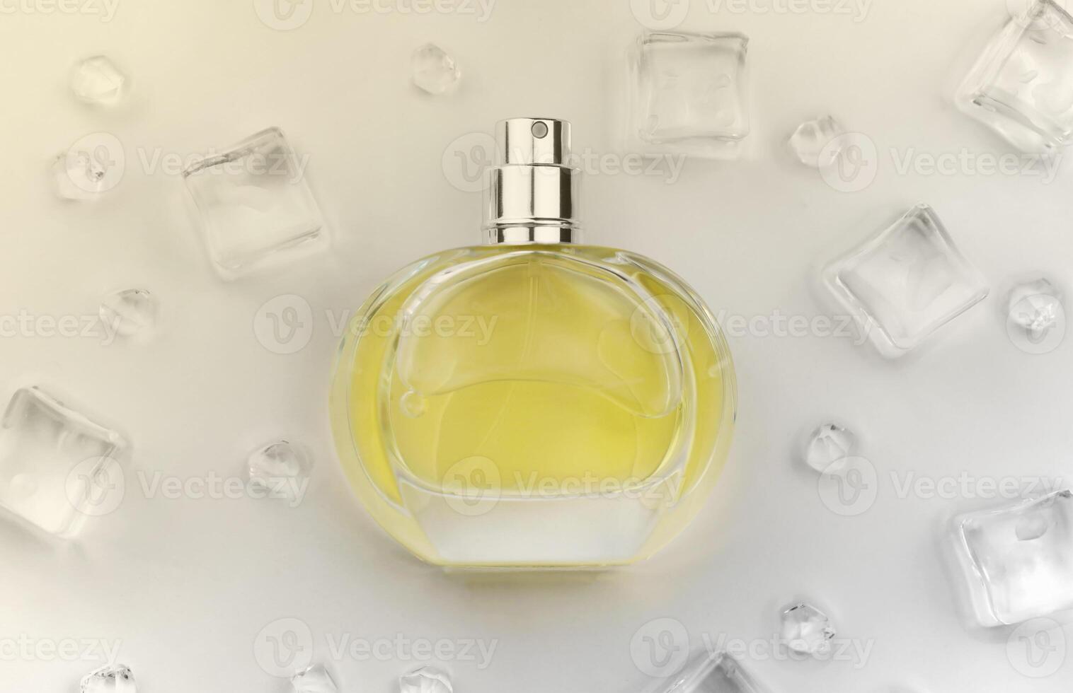 Female perfume yellow bottle, Objective photograph of perfume bottle in ice cubes and water on white table. View from above. Mockup product photo, concept of freshness photo
