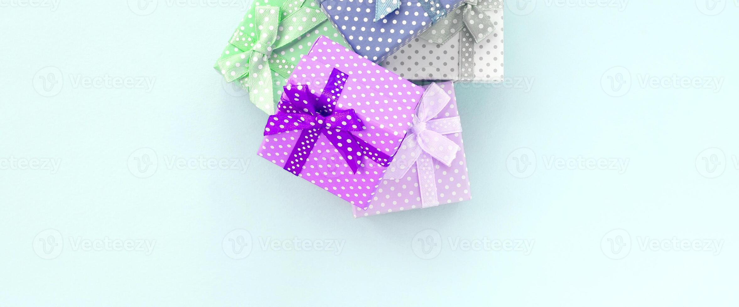 Pile of a small colored gift boxes with ribbons lies on a violet background. Minimalism flat lay top view photo