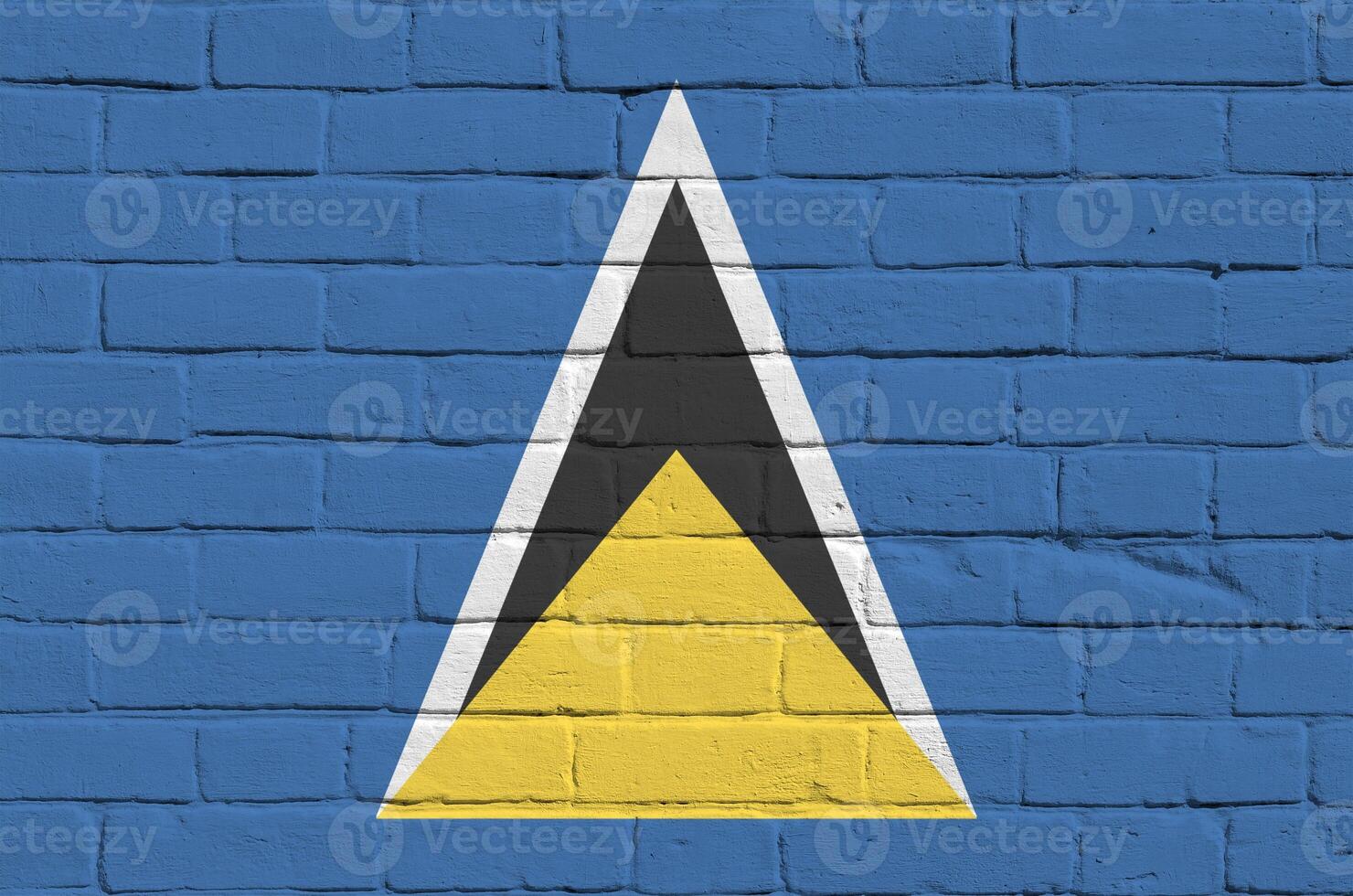 Saint Lucia flag depicted in paint colors on old brick wall. Textured banner on big brick wall masonry background photo