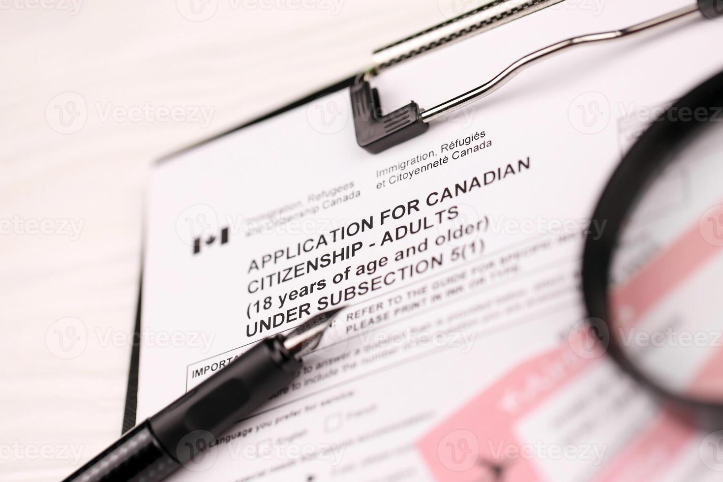 Application for Canadian citizenship for adults on A4 tablet lies on office table with pen and magnifying glass photo