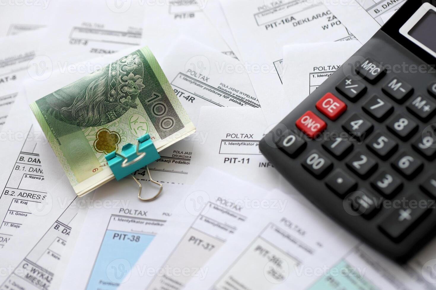 Polish zloty money PLN, calculator and pen on big amount of polish PIT, CIT and VAT tax forms close up. Accounting, bureaucracy and taxpayers routine photo