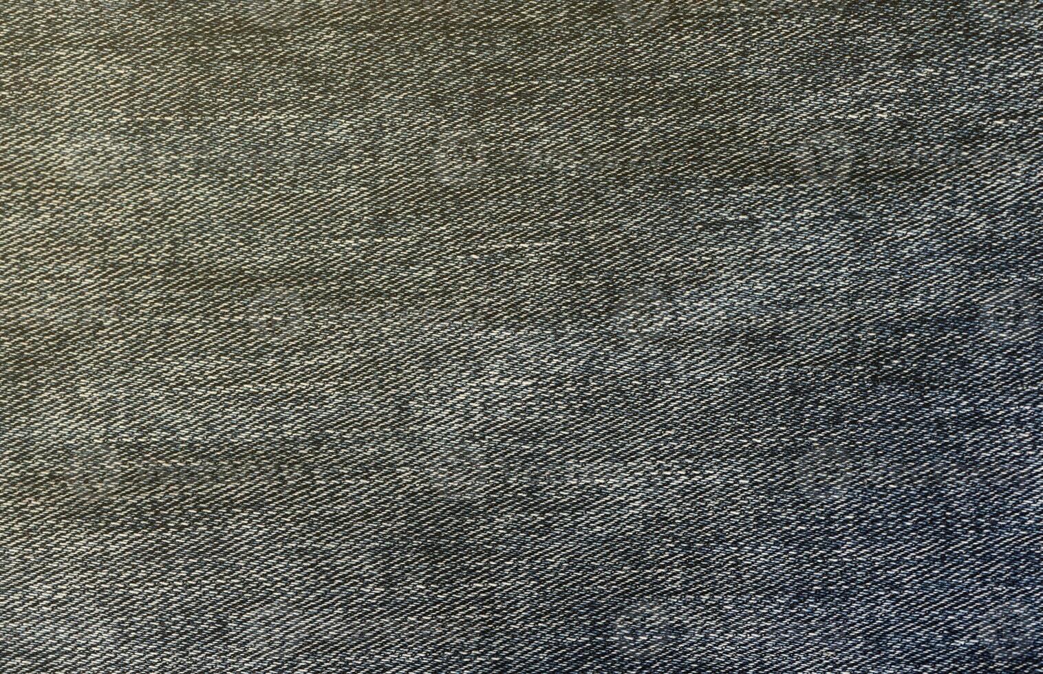 Detailed abstract texture of dark blue denim cloth. Background image of old used denim trousers fabric photo