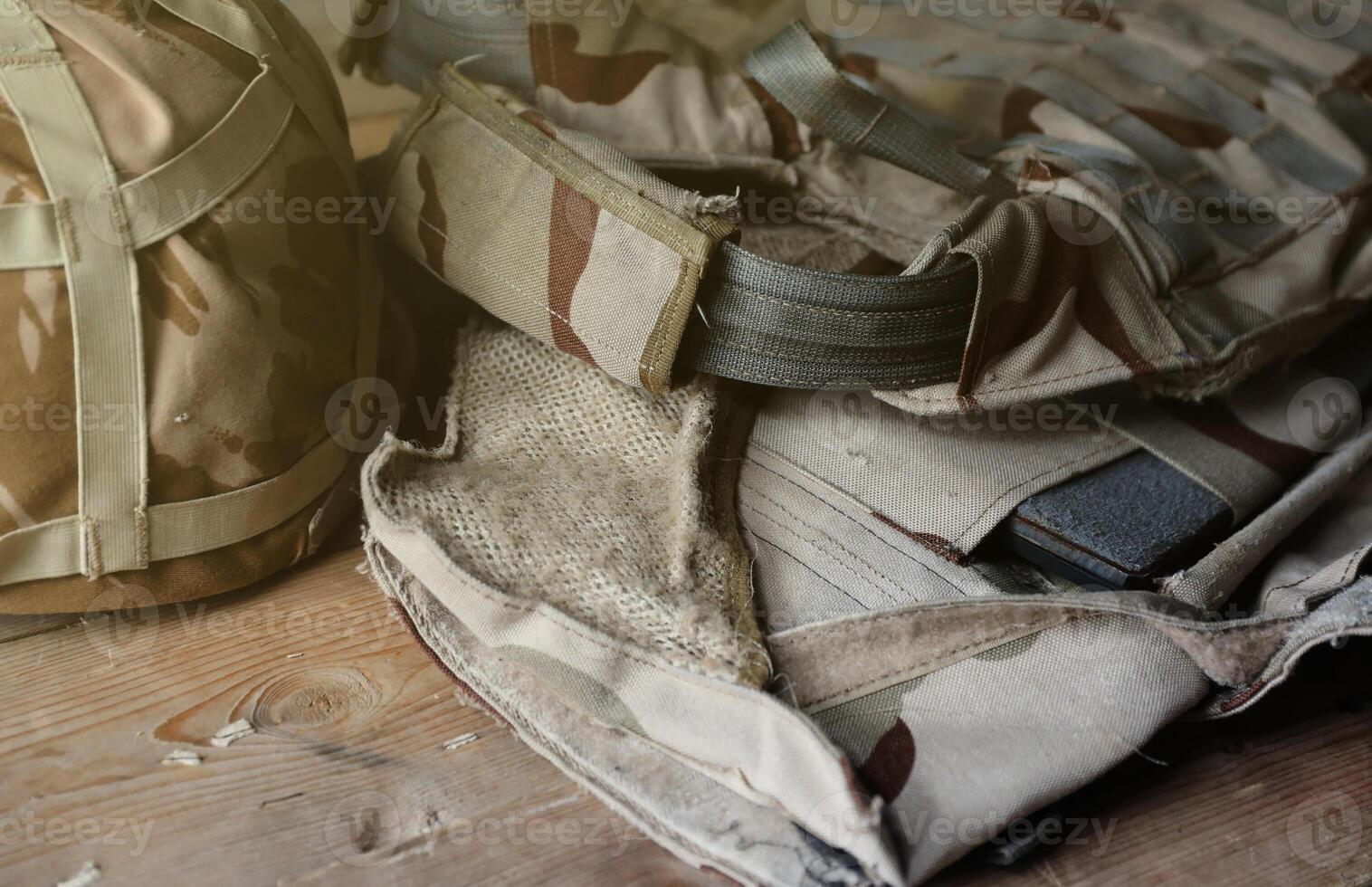 A military helmet of a Ukrainian soldier with a heavy bulletproof vest on wooden table in checkpoint dugout photo