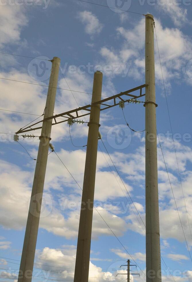 poste de hormigón con cables de línea eléctrica contra el fondo del cielo azul nublado foto
