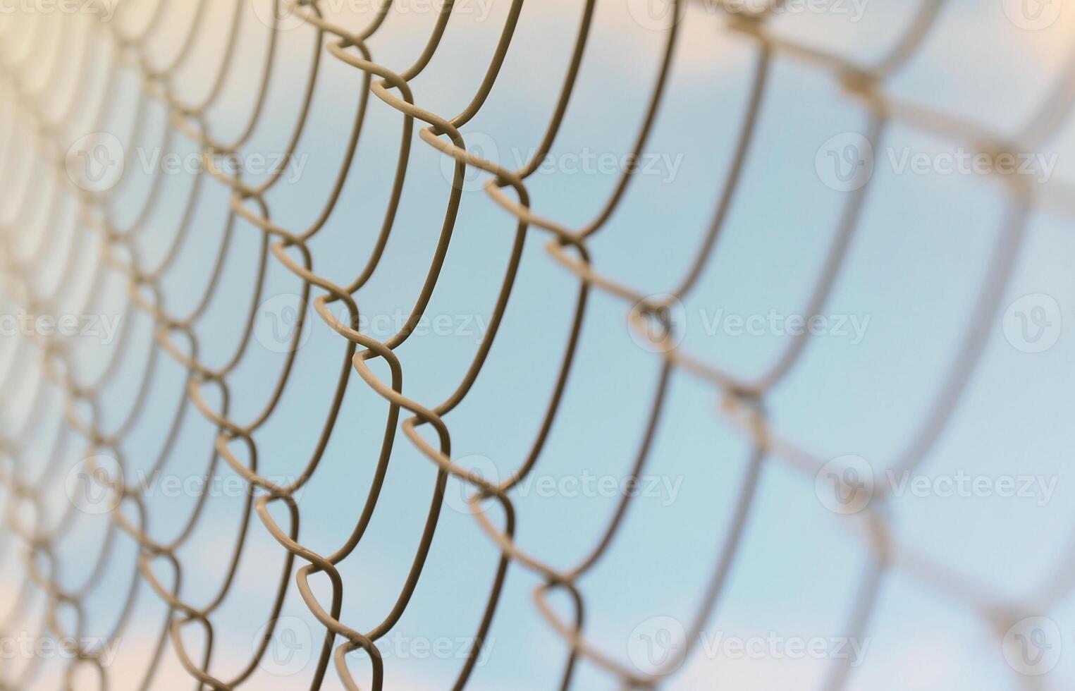 A photograph of a metal net used as a fence of private possessions. Old metal grid in perspective with a blurred background photo