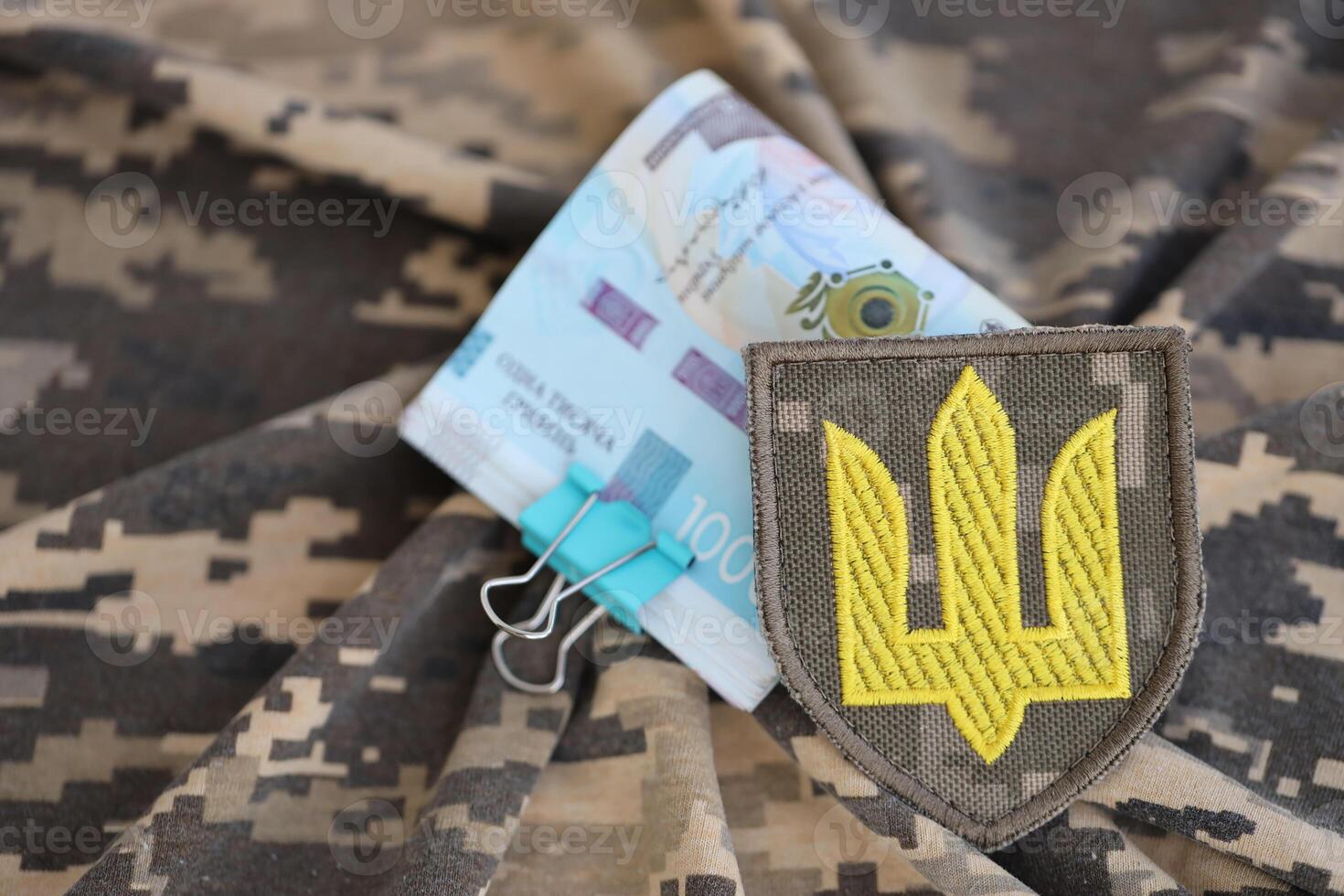 Ukrainian army symbol and bunch of hryvnia bills on military uniform. Payments to soldiers of the Ukrainian army, salaries to the military photo