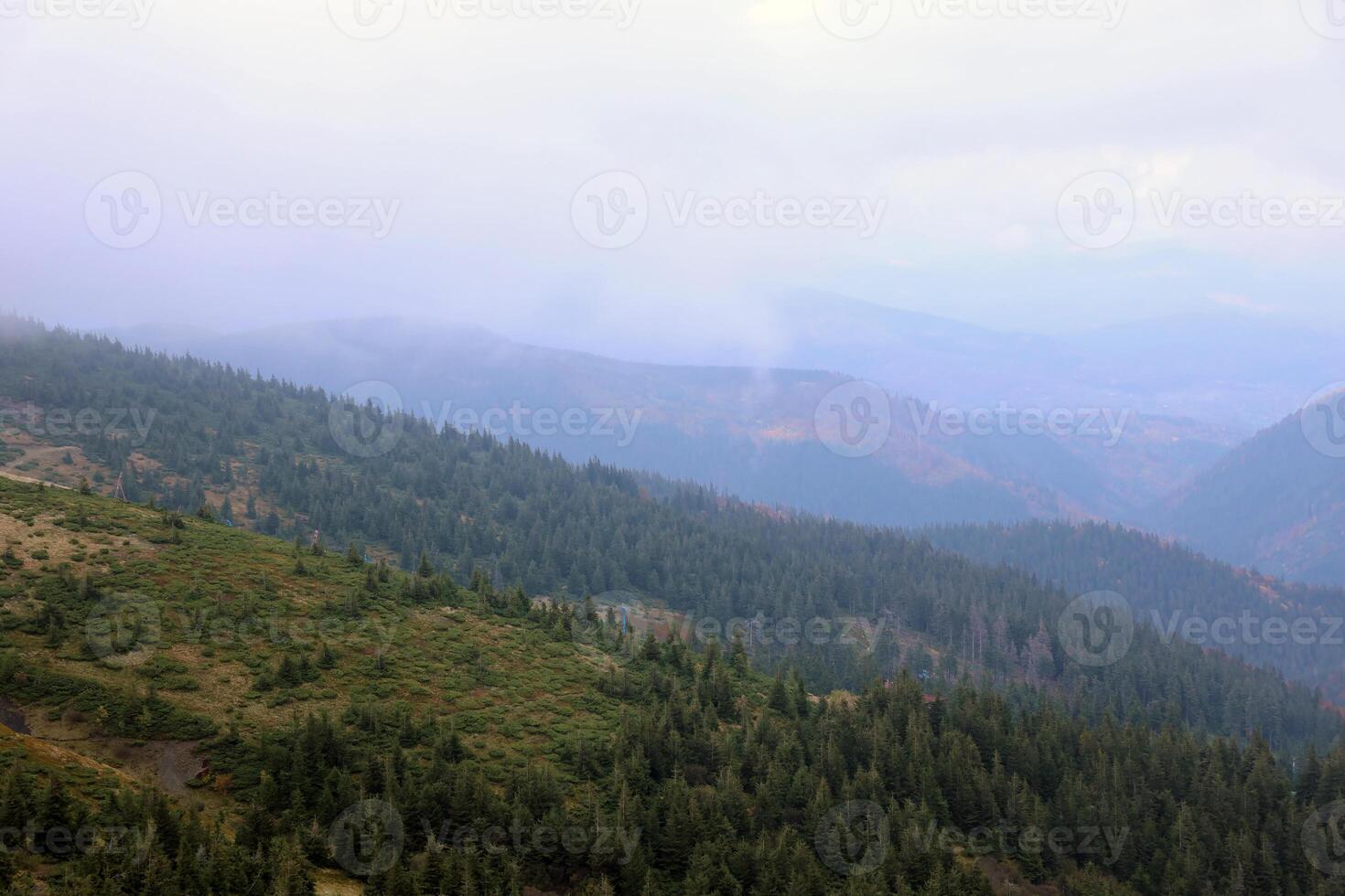 Morning view from the Dragobrat mountain peaks in Carpathian mountains, Ukraine. Cloudy and foggy landscape around Drahobrat Peaks photo