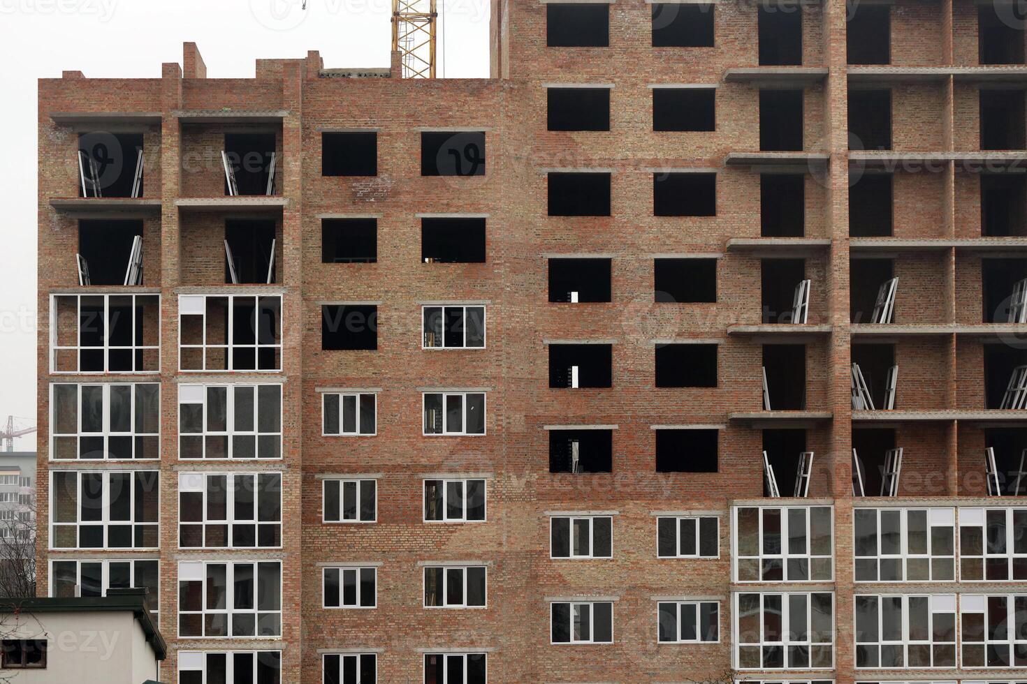View of a large construction site with buildings under construction and multi-storey residential homes. Tower cranes in action on blue sky background. Housing renovation concept photo