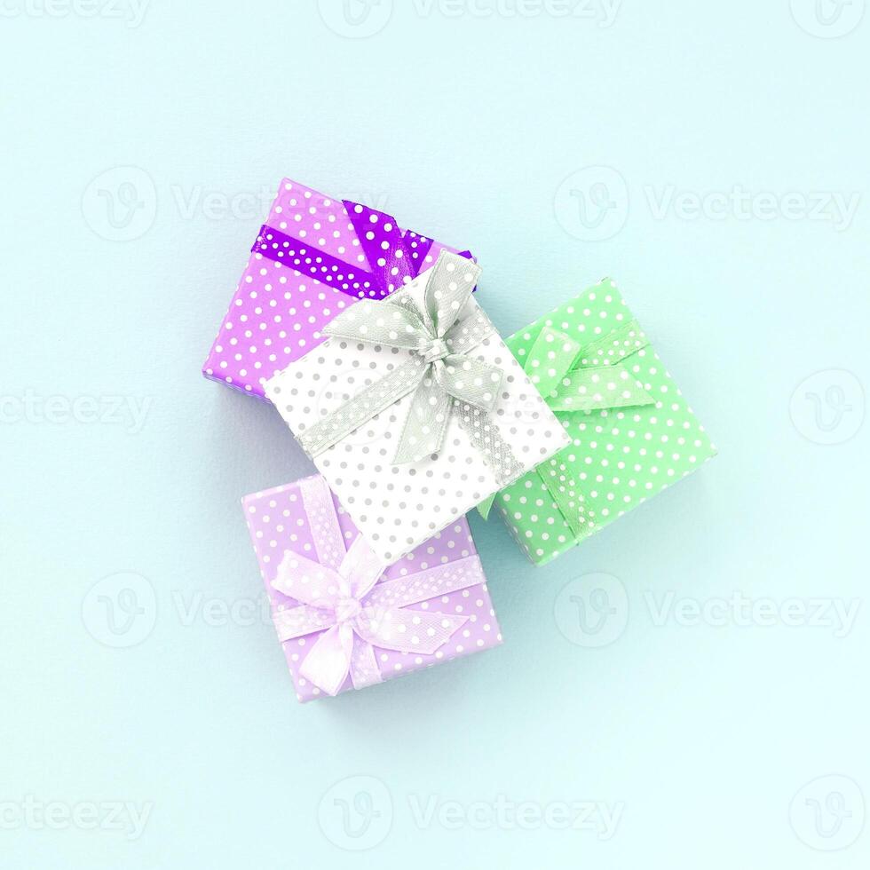 Pile of a small colored gift boxes with ribbons lies on a violet background. Minimalism flat lay top view photo