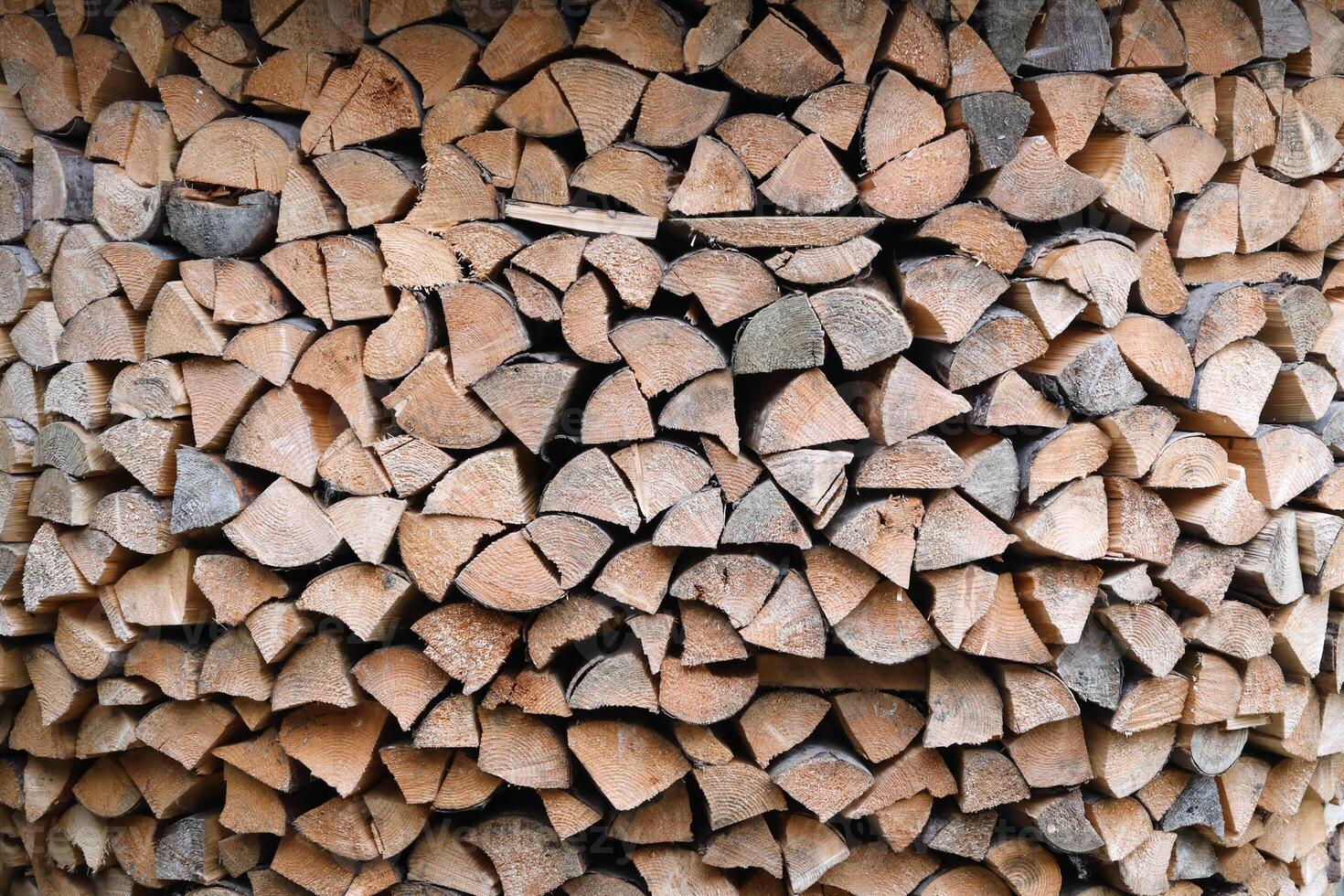 Firewood stacked near the wooden wall of old hut. Many chopped logs of firewood photo