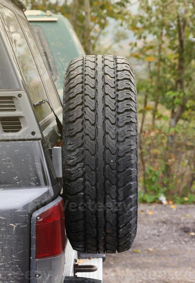 rueda de cerca en un campo paisaje con un barro la carretera. fuera del camino 4x4 suv automóvil con ditrito cuerpo después conducir en lodoso la carretera foto