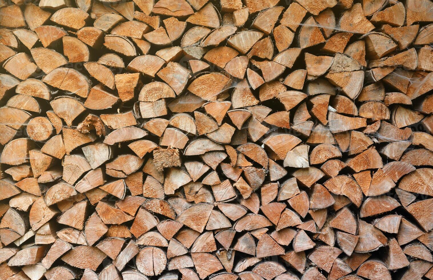 Firewood stacked near the wooden wall of old hut. Many chopped logs of firewood photo