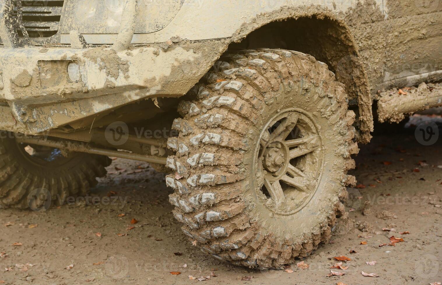 Wheel closeup in a countryside landscape with a mud road. Off-road 4x4 suv automobile with ditry body after drive in muddy road photo