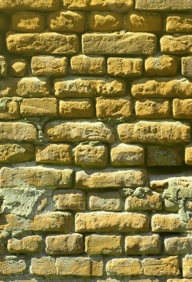 Vertical wall texture of several rows of very old brickwork made of red brick. Shattered and damaged brick wall with pinched corners photo