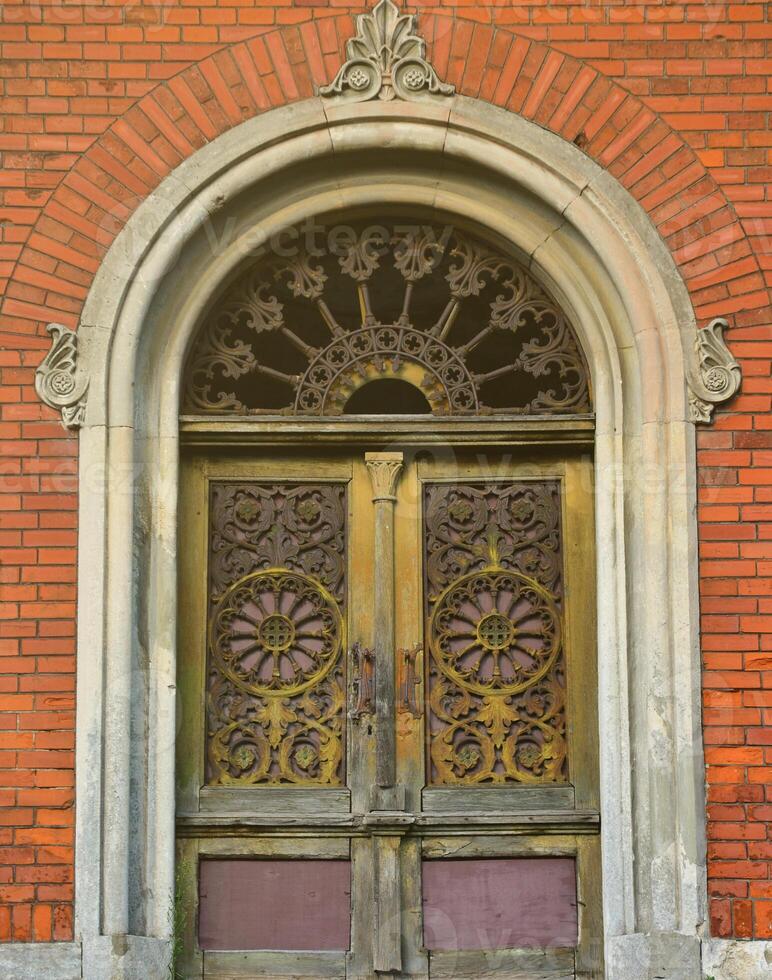 Texture front part of an ancient brick crypt with a patterned wooden door in the cemetery photo