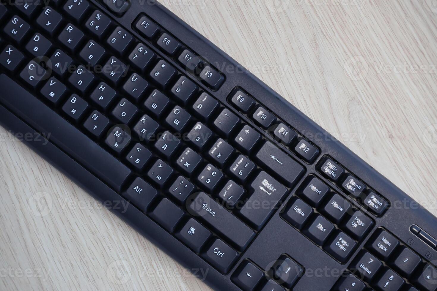 Small compact black gaming computer keyboard on a table made of wooden pine boards. Wireless keyboard with mechanical switches for gadgets and computer photo