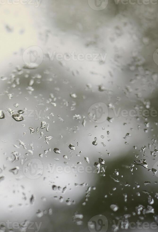 una foto de gotas de lluvia en el cristal de la ventana con una vista borrosa de los árboles verdes florecientes. imagen abstracta que muestra las condiciones meteorológicas nubladas y lluviosas