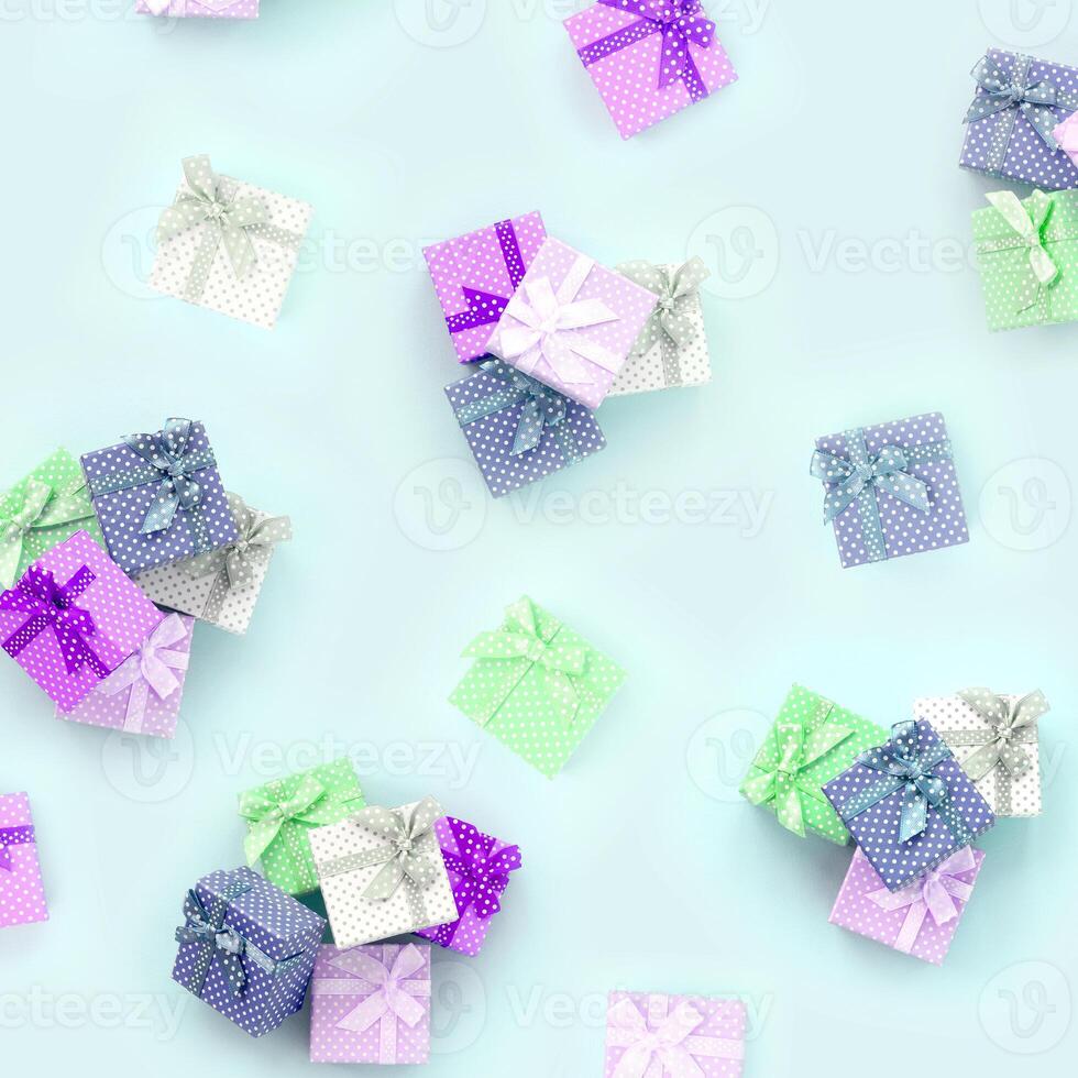 Piles of a small colored gift boxes with ribbons lies on a violet background. Minimalism flat lay top view pattern photo