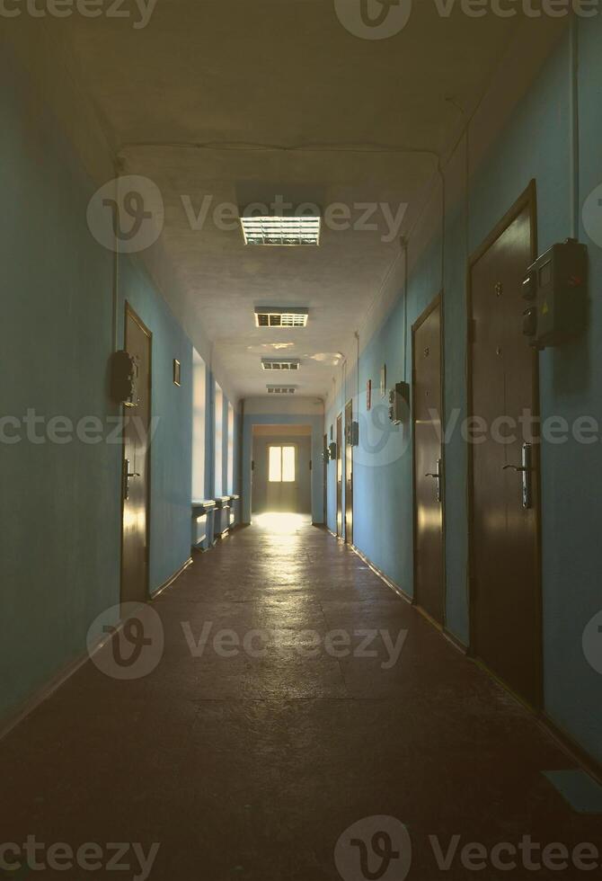 The gloomy corridor of a neglected public building. Public space in a poor residential high-rise building photo