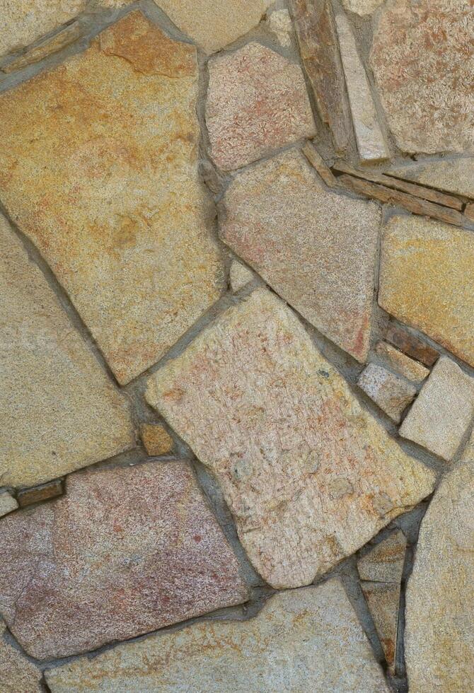 The texture of a strong stone wall of many concreted stones of various shapes photo