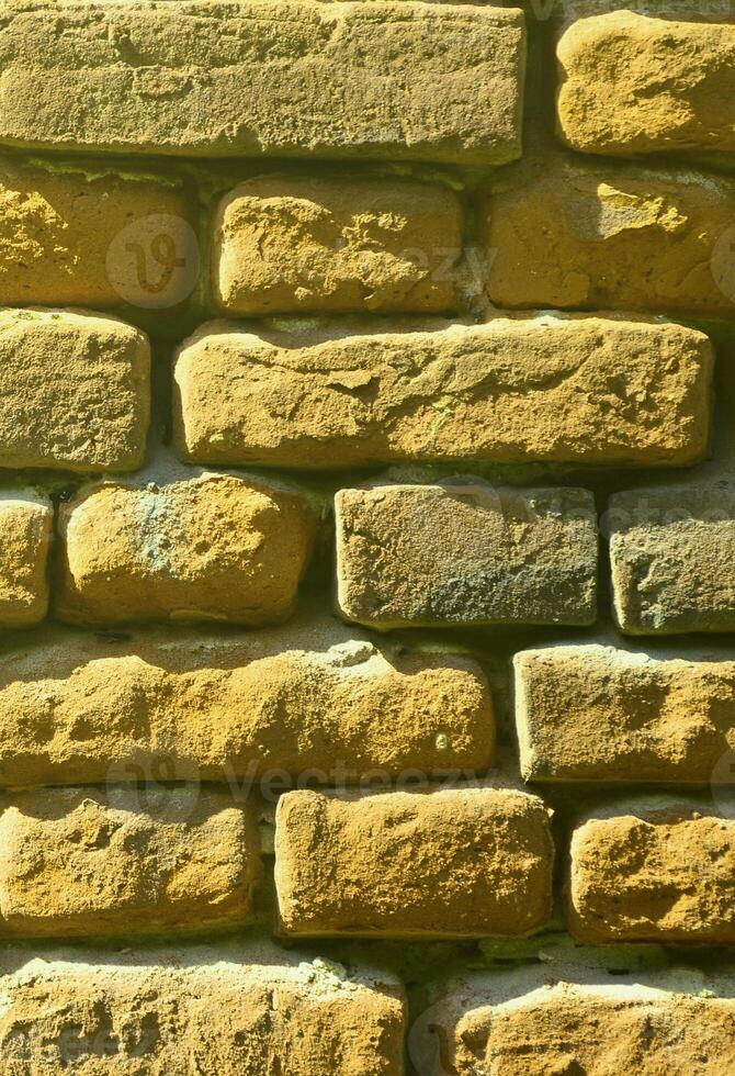 Vertical wall texture of several rows of very old brickwork made of red brick. Shattered and damaged brick wall with pinched corners photo