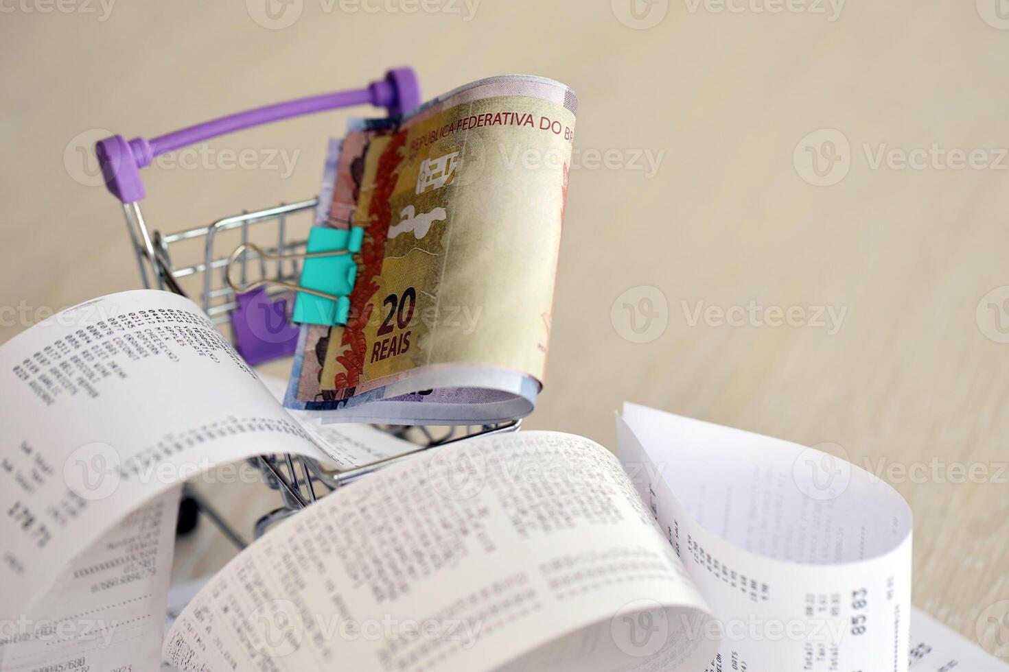 Brazilian reais money bills bunch in shopping trolley surrounded by many paper receipts photo