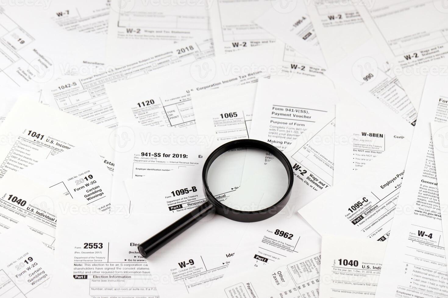 Magnifying glass lying over heap of paper documents. Investigation and financial audit photo