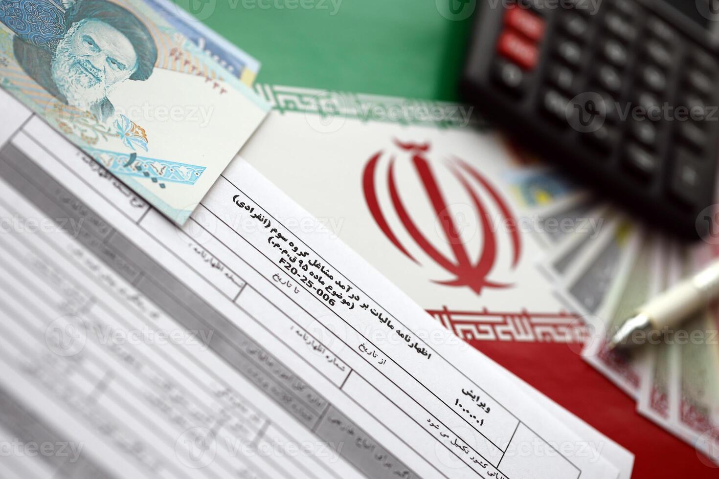 Iranian annual income tax return form F20-25-006 ready to fill on table with pen, calculator and iranian money on flag photo