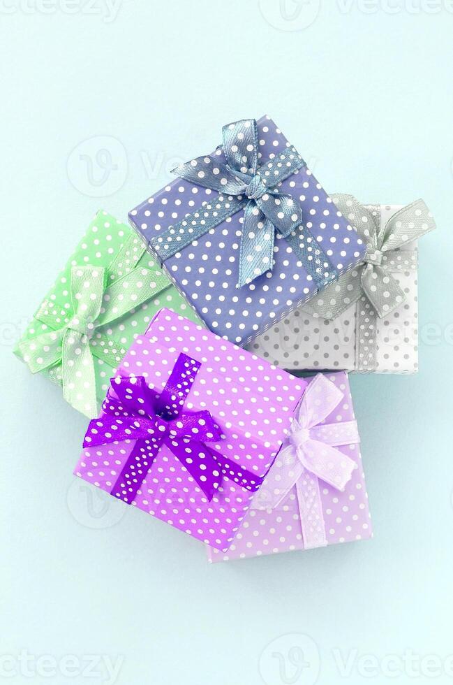 Pile of a small colored gift boxes with ribbons lies on a violet background. Minimalism flat lay top view photo