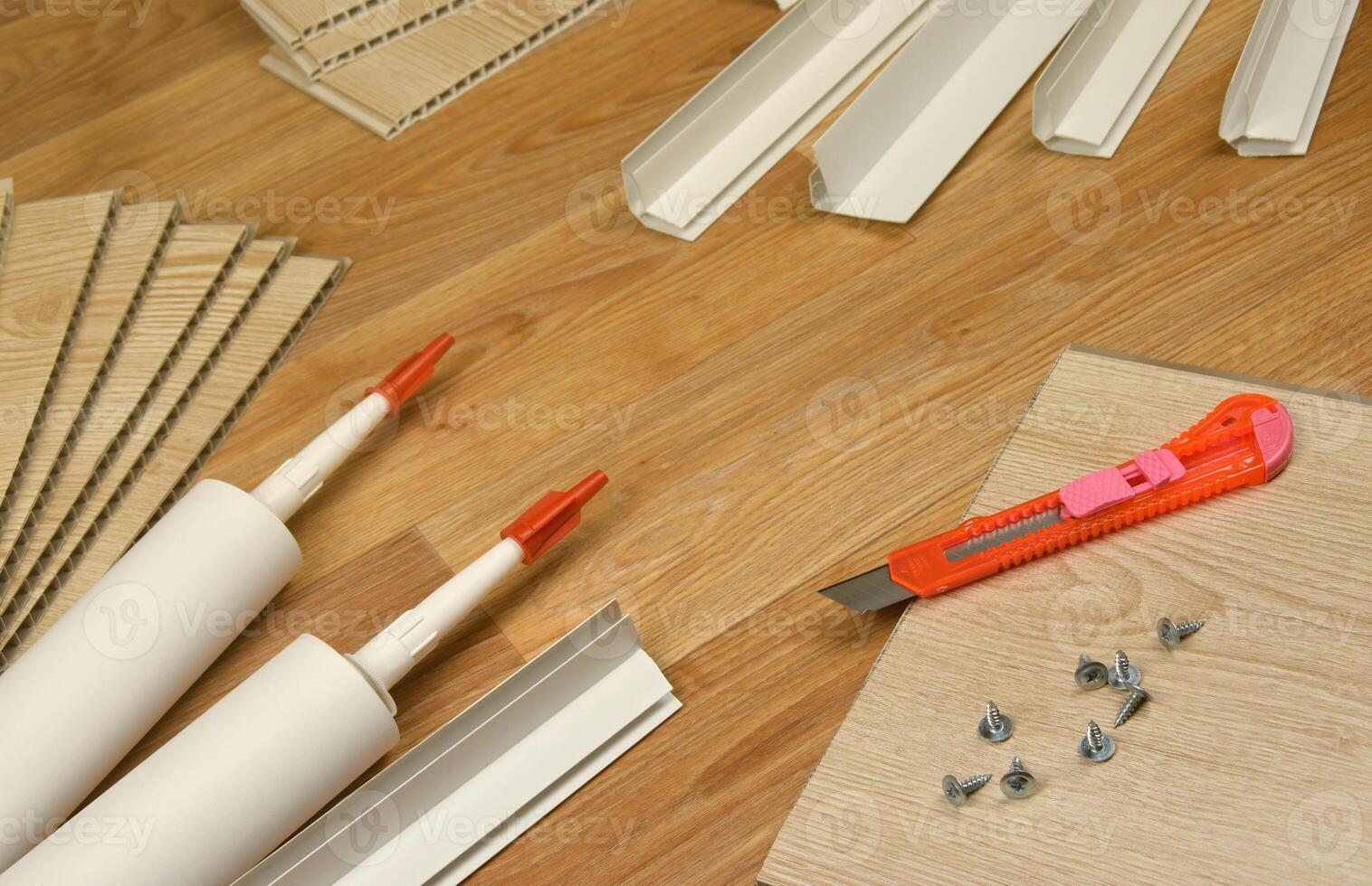 Set of items for PVC ceiling indoor works. Assembly adhesive bottles and PVC panels with plastic corners. Indoor VPC siding kit. Interior renovation works or construction photo