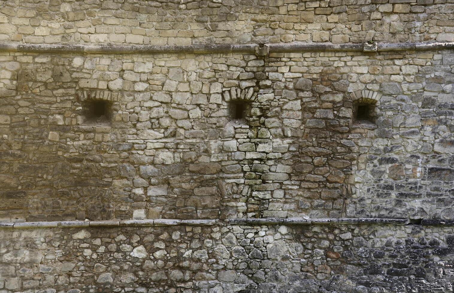 Very old brick stone wall of castle or fortress of 18th century. Full frame wall with obsolete dirty and cracked bricks photo