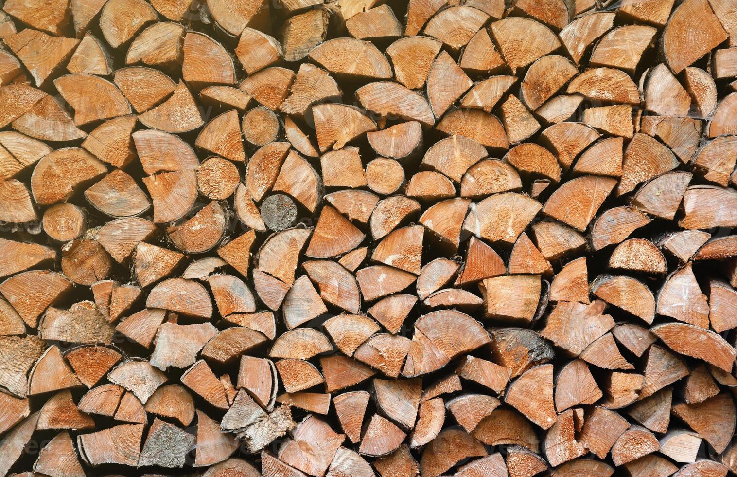 Firewood stacked near the wooden wall of old hut. Many chopped logs of firewood photo