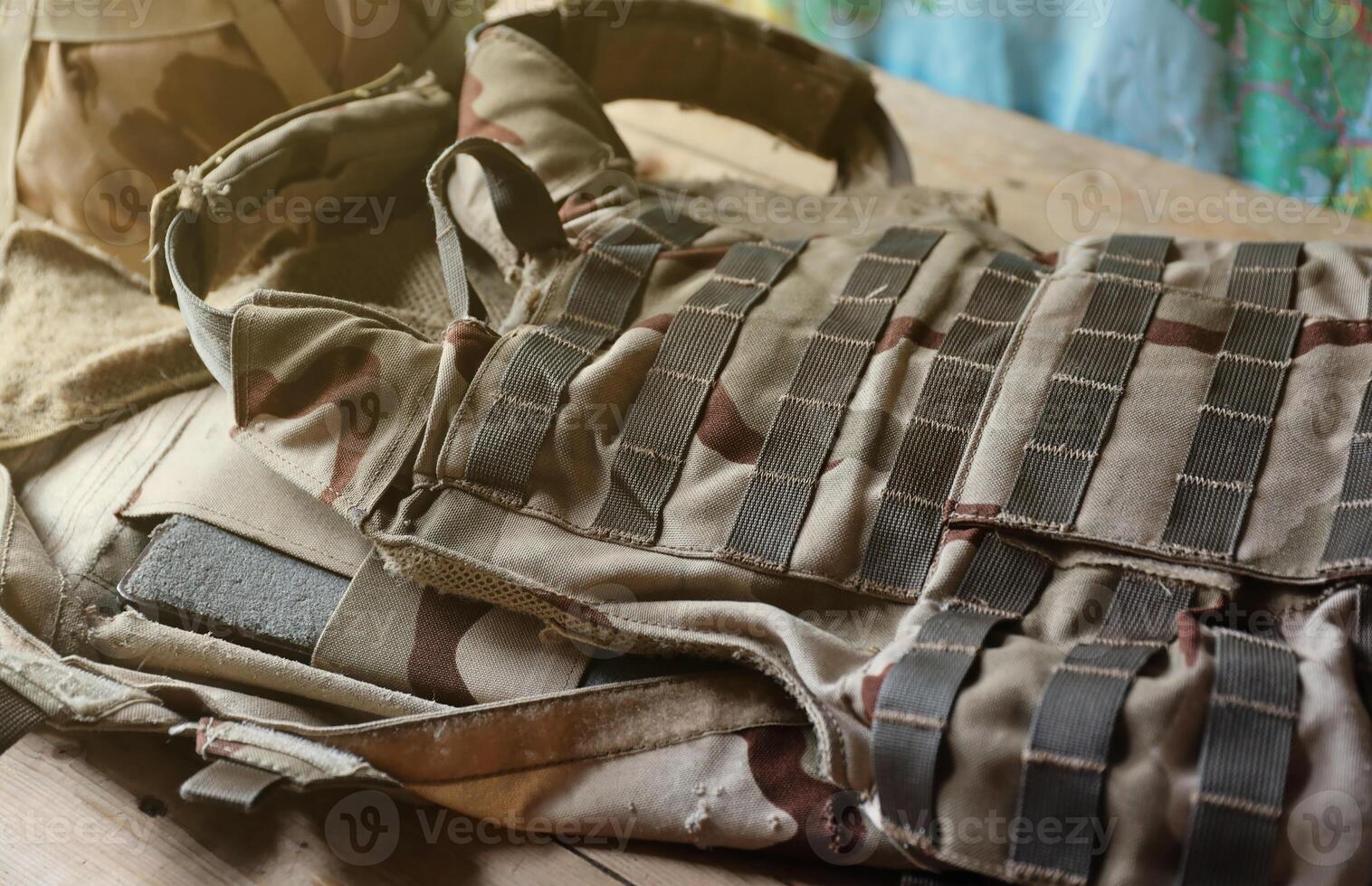 A military helmet of a Ukrainian soldier with a heavy bulletproof vest on wooden table in checkpoint dugout photo