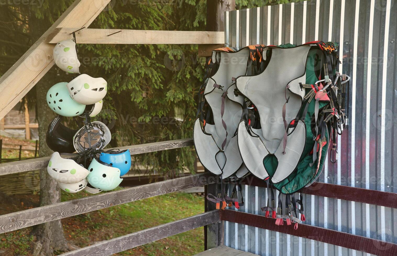 Climbing equipment - colorful helmets and safety vests hanging on a board in a rope park photo