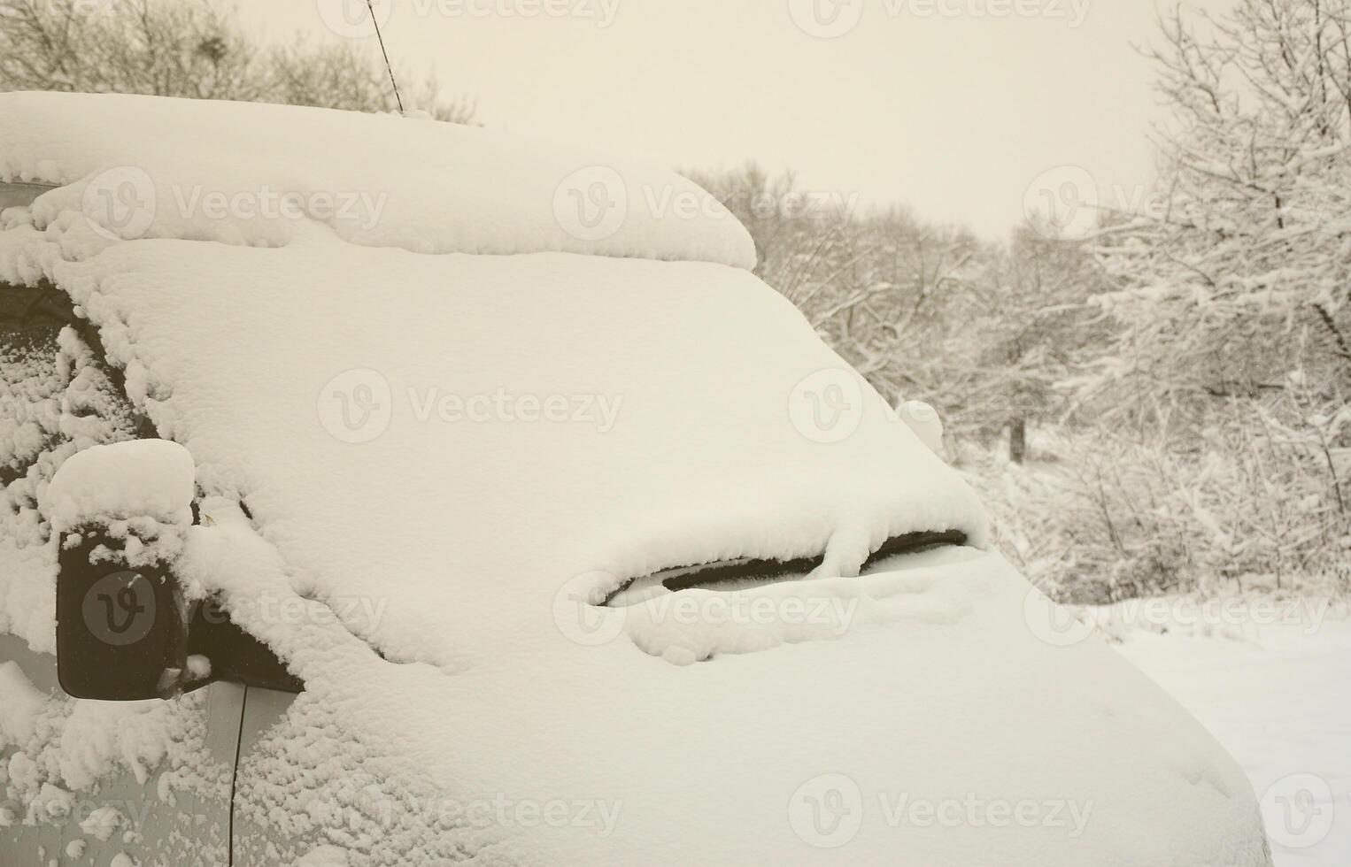 Fragment of the car under a layer of snow after a heavy snowfall. The body of the car is covered with white snow photo